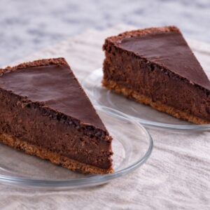 Two slices of chocolate cheesecake on plates.